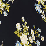 The Kieren Floral Maxi Dress by VERONICA BEARD features a vintage-inspired floral pattern with clusters of white roses, blue blossoms, and green leaves set against a solid black background, creating an elegant look perfect for any occasion.