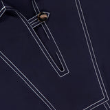 Close-up of the Phelix Topstitched Mini Dress by VERONICA BEARD, featuring dark navy stretch-cotton poplin, white contrast stitching, a pointed collar, geometric front design, neckline button detail, and a relaxed fit.