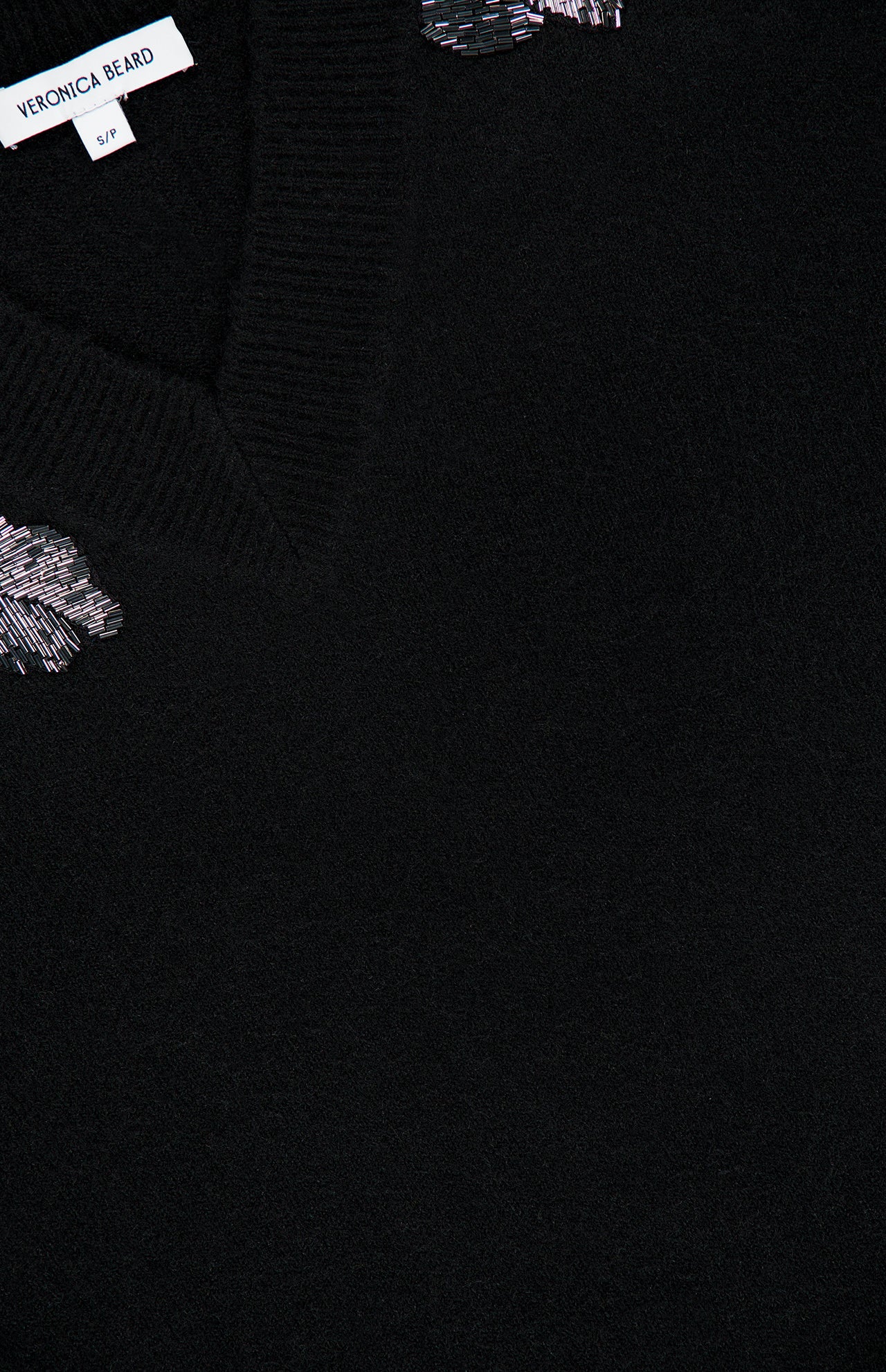 Veronica Beard Saelith Embellished Pullover Sweater in black, featuring a V-neck, stretch-wool blend, and floral beaded embroidery near the neckline.