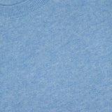 Close-up of the Shana Cropped Cashmere Sweater by VERONICA BEARD in light blue, highlighting its knit texture and neckline. A portion of the garment label with the brand name and size S/P appears at the top left corner. This relaxed fit sweater features a subtly cropped hem, offering a modern silhouette.
