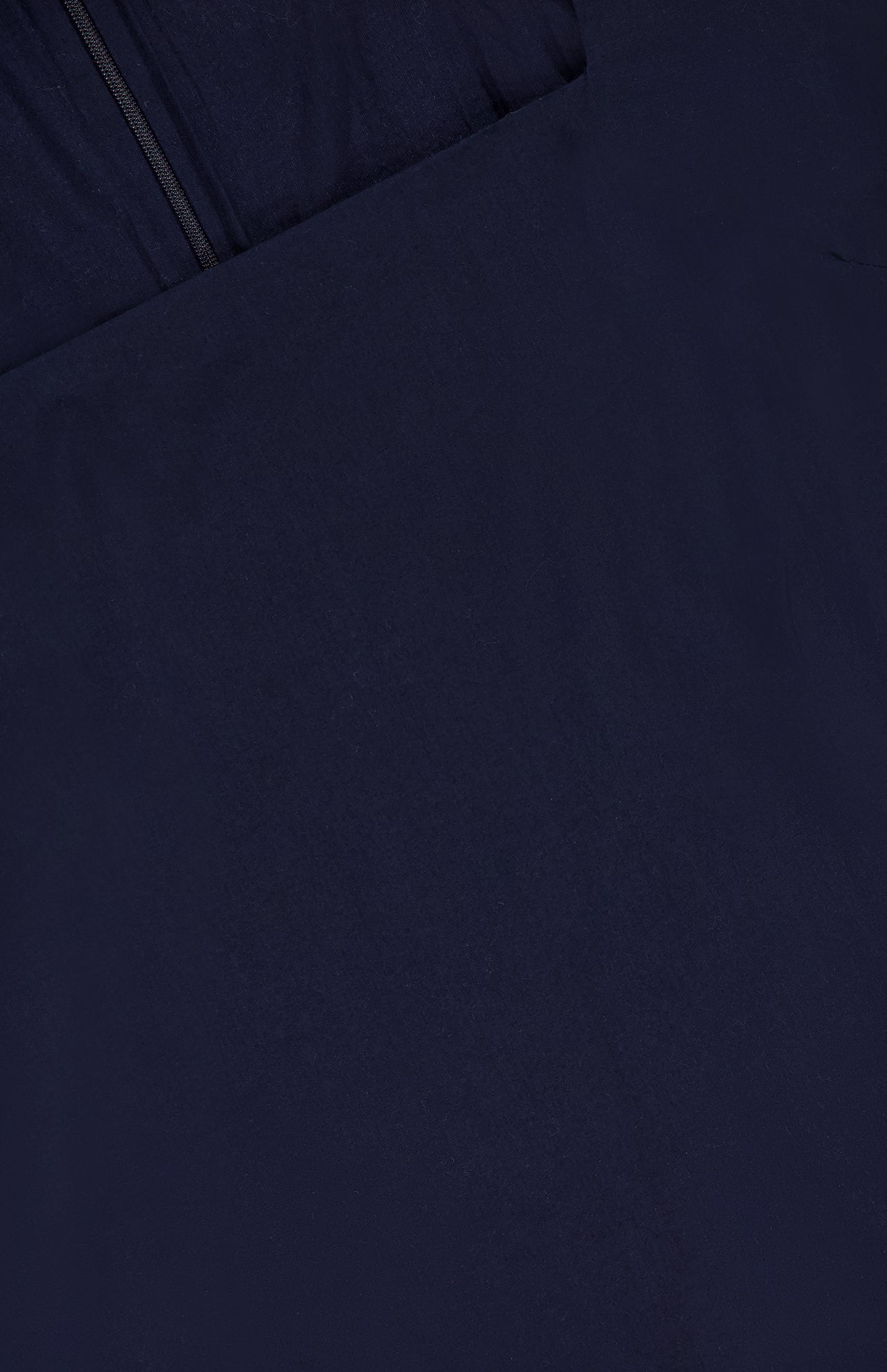 Close-up of the Shanice Scalloped Lace Hem Dress by VERONICA BEARD, featuring smooth, dark navy blue fabric with a visible seam and partial zipper at the top left corner. The sleeveless mini dress has a uniformly colored texture.