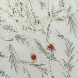 A close-up of the VERONICA BEARD Sleeveless Dominick Prairie Floral Dress shows light cotton-silk voile with pastel floral print, featuring two drawstrings with heart-shaped beads and lace trim.