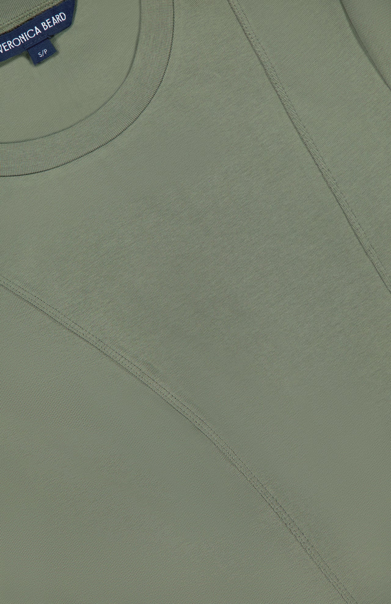 Close-up of the Syverin Asymmetrical Paneling T-shirt in olive green by VERONICA BEARD, size S/P, featuring visible stitched seams and a branded label at the collar.