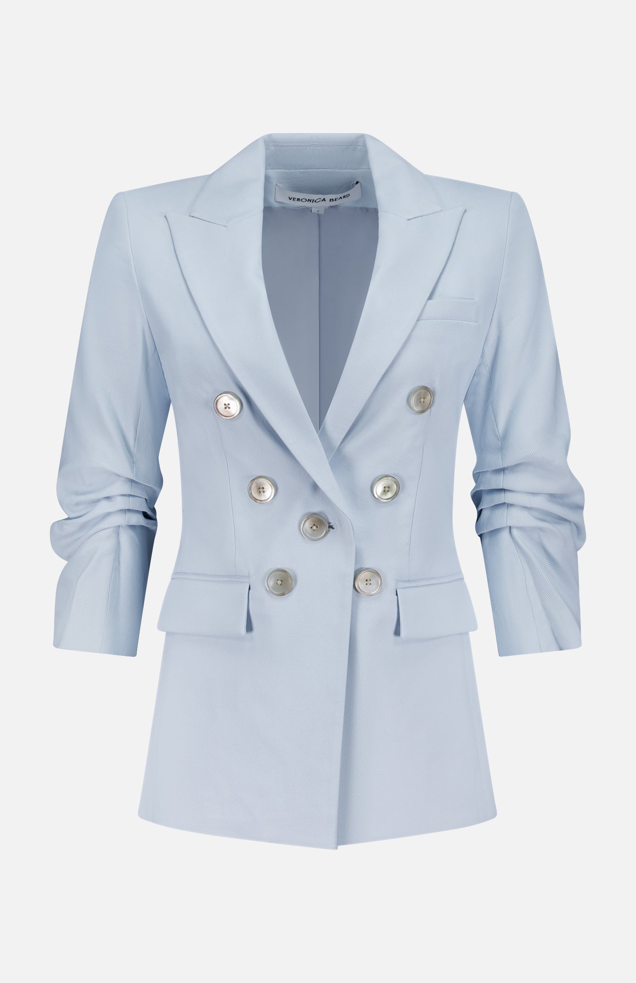 The Tomi Dickey Jacket by VERONICA BEARD is a pale blue Italian twill blazer, double-breasted with silver buttons, notched lapels, ruched long sleeves, two front flap pockets, dickey compatible, shown on a plain white background.