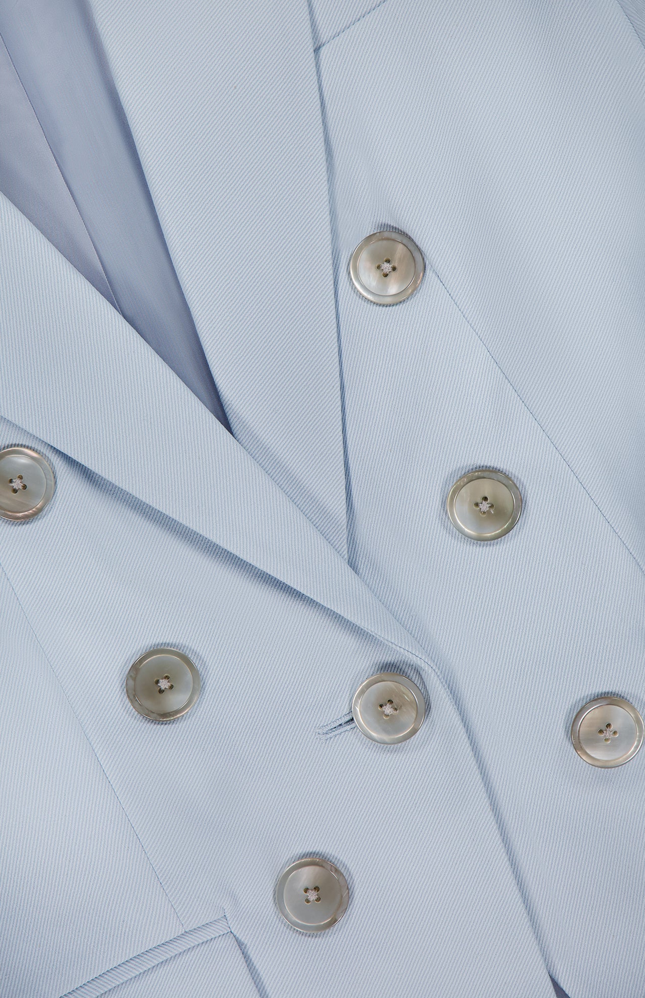 Close-up of the VERONICA BEARD Tomi Dickey Jacket in pale blue Italian twill, featuring six shiny silver buttons in two rows and part of the lapel; this blazer is also dickey compatible.