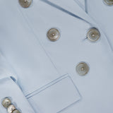 Close-up of the Tomi Dickey Jacket by VERONICA BEARD, in pale blue Italian twill. Features metallic buttons, a front pocket, textured fabric, and is dickey compatible for versatile styling.