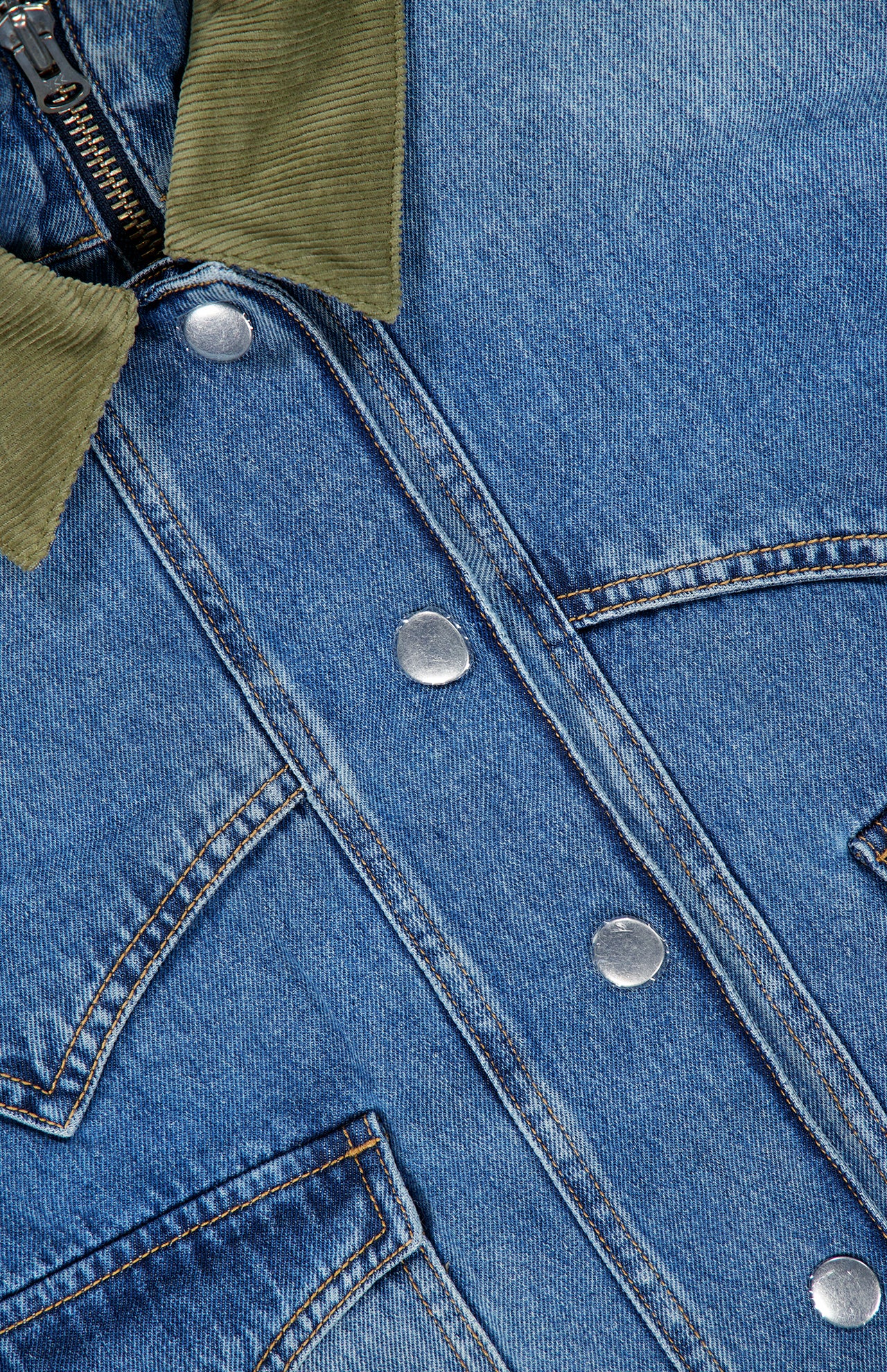 Close-up of the Wegner Double Collar Denim Jacket by VERONICA BEARD, showcasing its blue denim fabric with a distinctive green corduroy collar, silver snap buttons, visible pockets, and brown stitching—this stylish jacket puts a modern spin on the classic jean style with its unique double collar design.