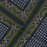 The Yvonne Scarf Print Top by VERONICA BEARD features colorful fabric adorned with diagonal green and blue stripes, small gold dots, and intricate paisley and floral patterns in orange, white, and black, creating a vibrant geometric design reminiscent of a luxurious scarf print or an asymmetrical silk blouse.