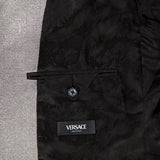 Close-up of the Metallic Evening Tux Jacket by VERSACE shows its elegant floral lining, buttoned pocket, and black VERSACE label. The luxurious interior contrasts with shiny silver fabric, emphasizing the jacket's sophisticated metallic style.