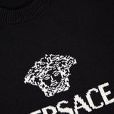 Close-up of the black VERSACE Medusa Cashmere Knit Sweater, showcasing the white Medusa logo and VERSACE text knitted on the front; brand label visible inside the collar.