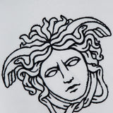 The VERSACE Cotton Jersey Medusa Embroidery T-Shirt features a black embroidered outline of the mythological Medusa head with snake hair on white fabric, capturing the essence of luxury Italian fashion.