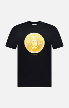 Introducing the VERSACE Cotton Medusa Coin Jersey T-Shirt: a black tee adorned with a striking gold Medusa coin emblem at the center and subtle yellow “VERSACE” lettering below—an iconic example of luxury Italian men’s fashion.