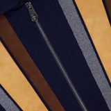 Close-up of a VERSACE Leather Patchwork Knit Jacket with a vertical zipper and bold navy, tan, brown, and gray stripes. The VERSACE label at the top left underscores this luxury Italian menswear piece.