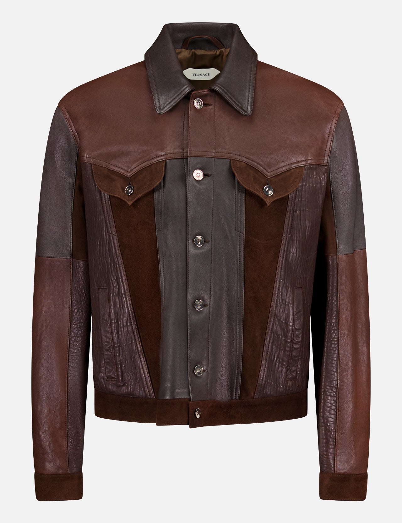 The VERSACE Leather Unit Mix Trucker Jacket is a men’s slim-fit piece crafted from brown leather and suede in varied shades, featuring a button-up front, pointed collar, flap chest pockets, and long sleeves for a polished look.