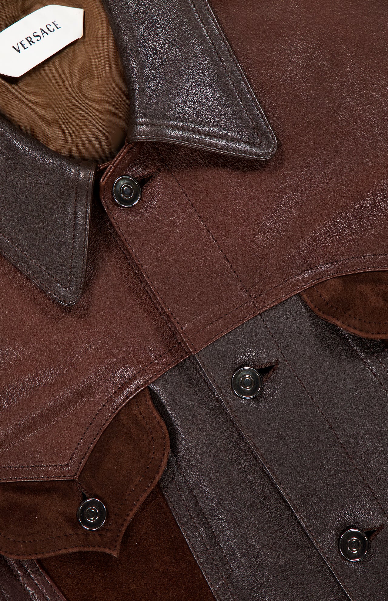 Close-up of the VERSACE Leather Unit Mix Trucker Jacket, highlighting its luxe leather and suede textures, black buttons, collar details, and an inner VERSACE label—a refined slim fit design for men.