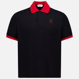The VERSACE Medusa Logo Embroidery Piquet Polo Shirt is a black short-sleeve polo with a red collar, red sleeve trim, and a small red Medusa logo on the left chest—a statement of luxury Italian style.