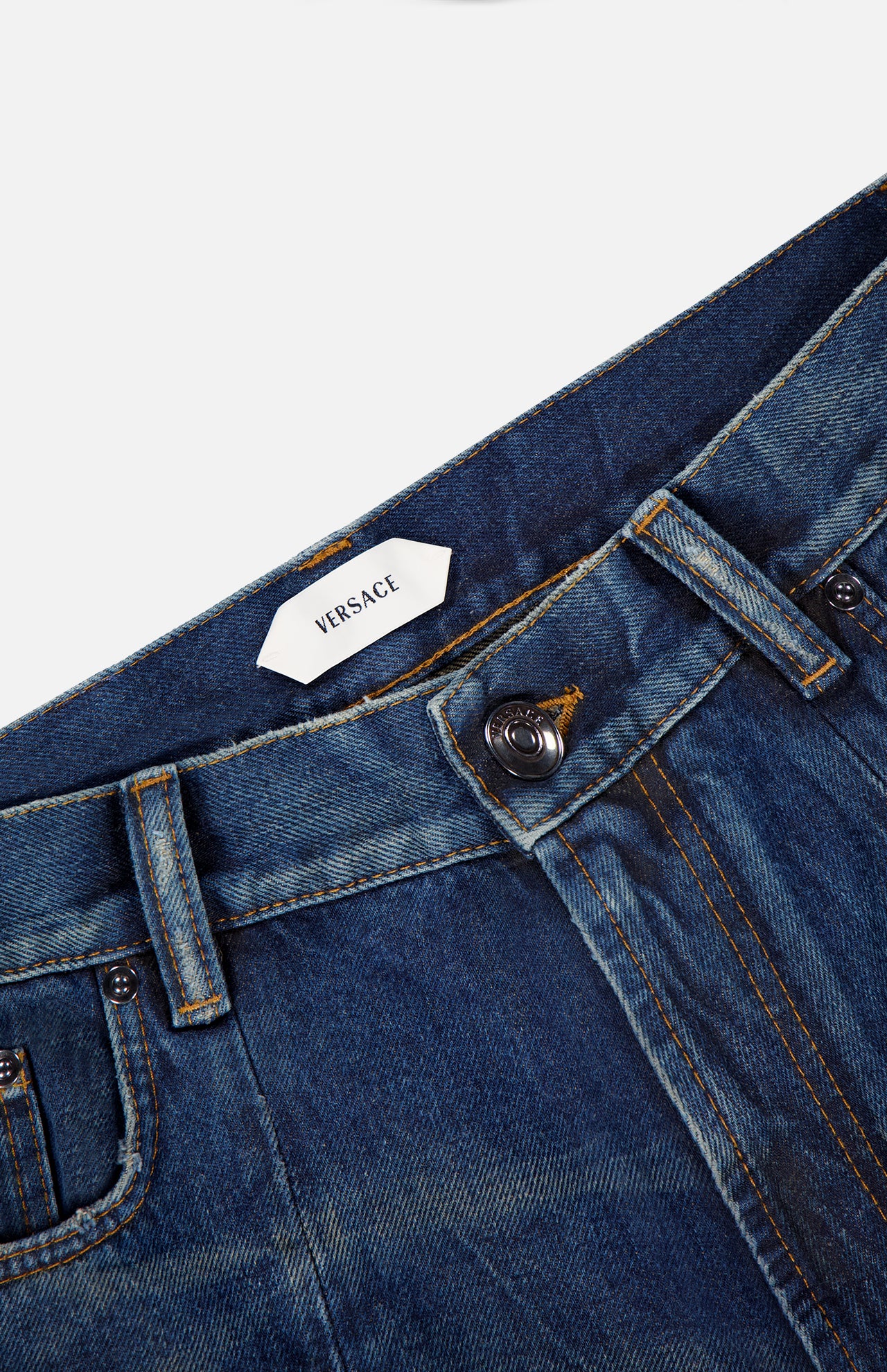 Close-up of the waistband and front pocket on VERSACE Non-Stretch Dirty Wash Jeans in Dirty Blue, showcasing the brand label, button, zipper, and detailed yellow stitching on vintage-effect denim.