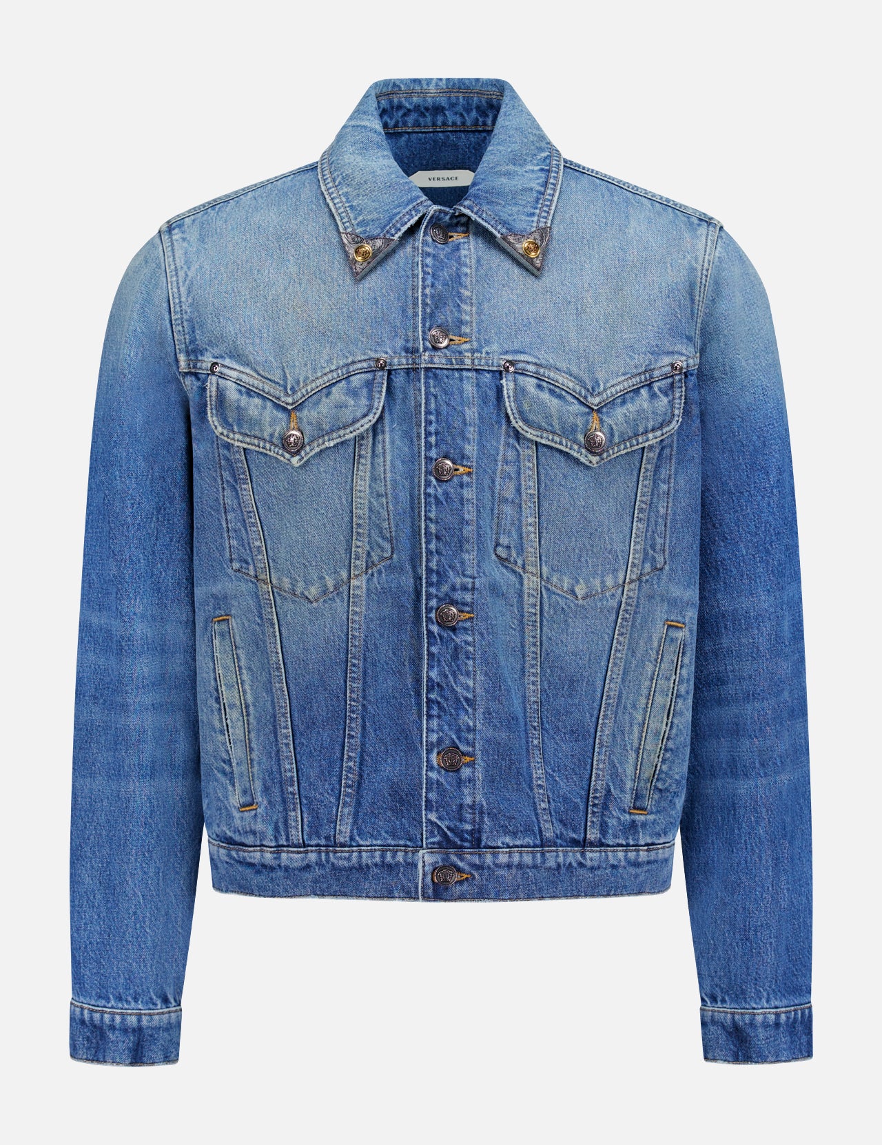 The VERSACE Rigid Stone Washed Denim Jacket features long sleeves, front button closure, Medusa hardware, two chest flap pockets, and side pockets in blue denim, shown against a plain white background.