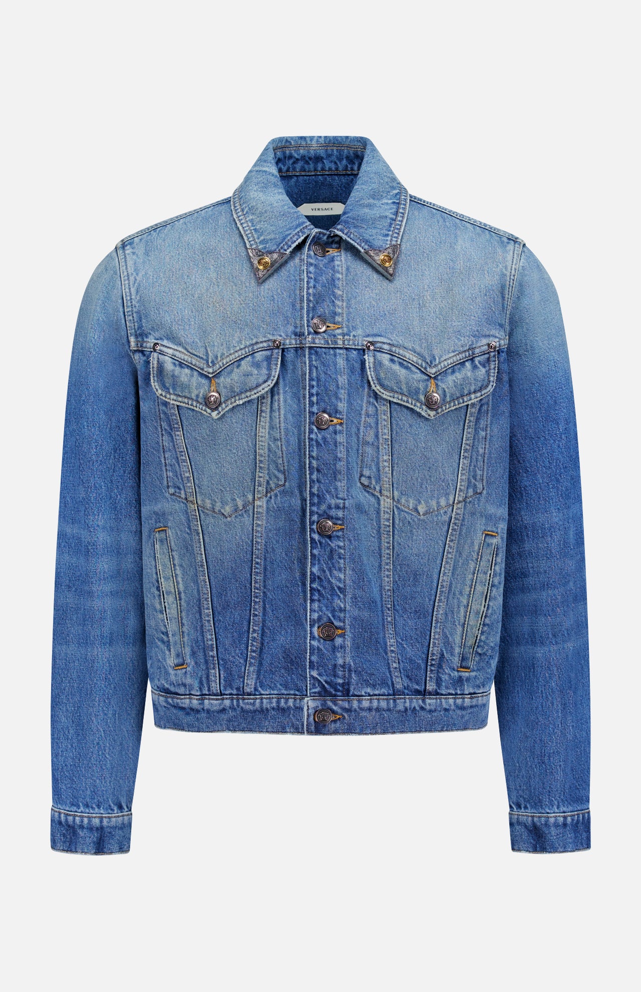 The VERSACE Rigid Stone Washed Denim Jacket features long sleeves, front button closure, Medusa hardware, two chest flap pockets, and side pockets in blue denim, shown against a plain white background.