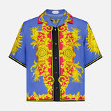 The VERSACE Silk Twill Print The Sun Shirt features short sleeves, a vibrant blue Baroque print with sun motifs, and black and red accents—luxury Italian menswear in a statement-making design.
