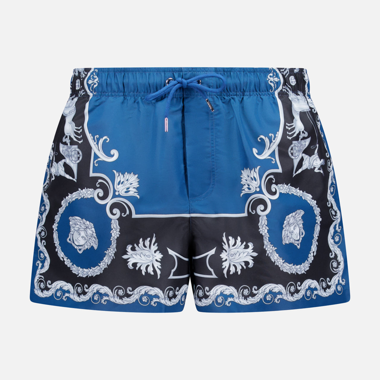 VERSACE Mythic Barocco Print Swim Shorts: blue and black with a white ornate floral and scroll baroque motif, featuring a drawstring waistband and mid-thigh length. Luxury Italian swimwear style.
