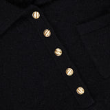 Close-up of the WHITE + WARREN Cashmere Gold Button Polo Top in black, featuring four gold-tone buttons and a small chest pocket; “WHITE + WARREN” label visible in the top left corner.