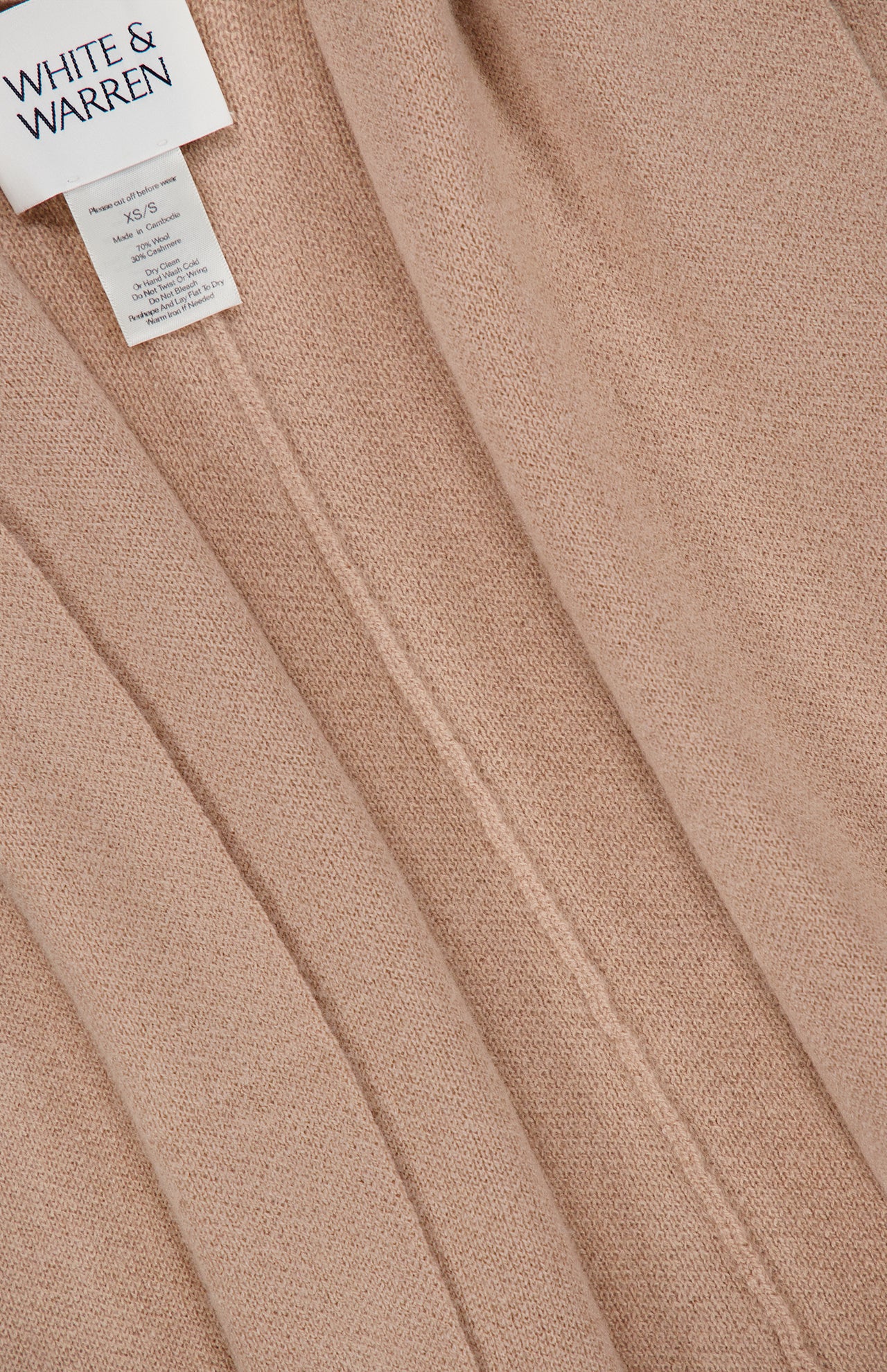 Close-up of a beige Cashmere Blend Poncho with Attached Scarf by WHITE + WARREN. The soft texture and seams are visible, showcasing the garment’s fine craftsmanship and neutral tone. Expertly crafted from a luxurious cashmere blend, this versatile piece is an ideal gift for women.