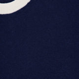 Close-up of a navy sweater featuring a white ribbed crewneck collar. A tag in the corner reads WHITE + WARREN, emphasizing the premium quality of this Cashmere Blend Relaxed Crewneck Sweater.