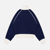 The Cashmere Blend Track Jacket by WHITE + WARREN, featuring a navy blue design with contrasting white cuffs, hem, and collar in the style of a classic knit track jacket, is displayed from the back against a plain white background.