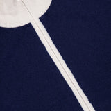 Close-up of the WHITE + WARREN Cashmere Blend Track Jacket in navy, featuring striking white accents and a visible vertical zipper. The ribbed white collar at the top and contrasting white lines on the rich knit fabric highlight the sporty, elevated design of this premium track jacket.