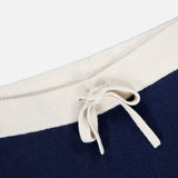 Close-up of the drawstring waist on the WHITE + WARREN Cashmere Blend Track Pants, featuring a cream-colored ribbed fabric and matching drawstring tied in a bow, set against navy fabric.