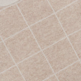 Close-up of the Cashmere Blend Windowpane Sweater by WHITE + WARREN in beige, featuring a subtle white grid pattern. A portion of the WHITE + WARREN label is visible at the collar. The cozy knit top looks soft and textured.