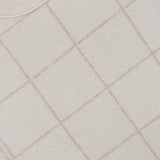 A close-up of the Cashmere Blend Windowpane Sweater by WHITE + WARREN, featuring a beige knit with a light brown windowpane grid pattern crafted from a luxurious wool-cashmere blend. The cozy sweater displays the signature WHITE + WARREN label near the collar.