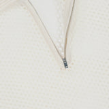 Close-up of the WHITE + WARREN Cashmere Mesh Polo Shirt, featuring a textured off-white mesh construction. The partially unzipped neckline reveals inner fabric, while a tag in the top left corner displays the brand name.