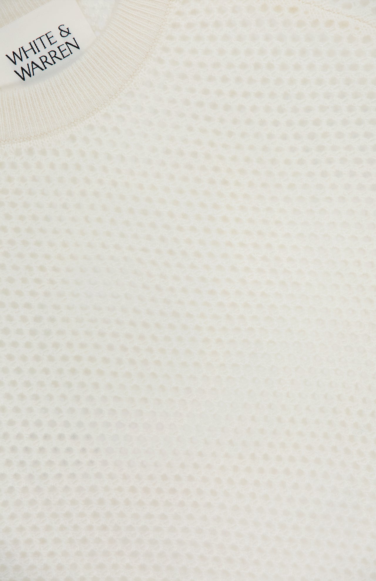 Close-up of the WHITE + WARREN Cashmere Mesh Sweatshirt in off-white, featuring a textured honeycomb pattern and mesh construction. The neckline label displays the brand name.