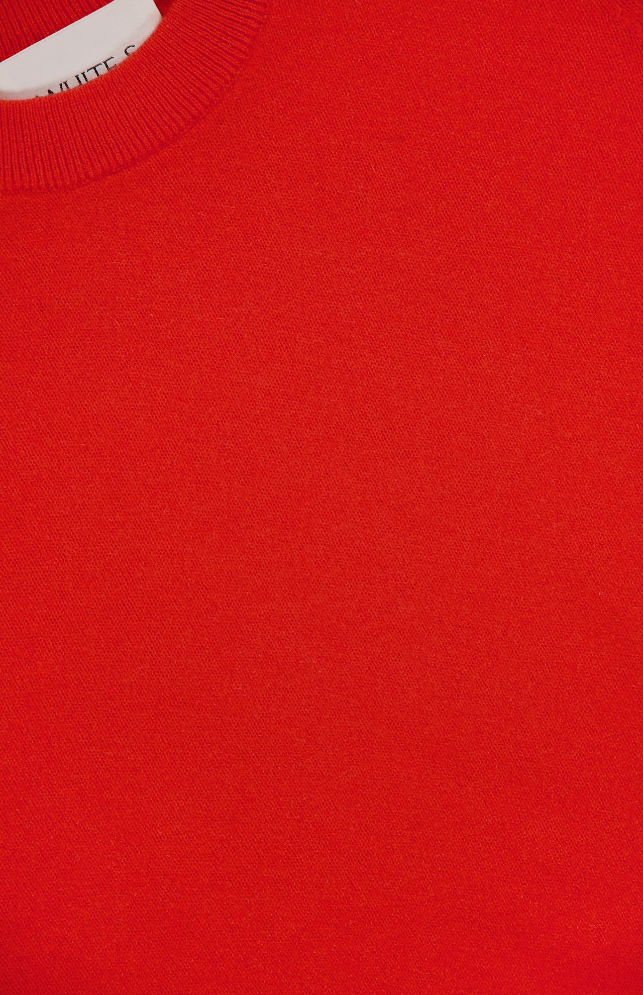 Close-up of the WHITE + WARREN Cashmere Relaxed T-Shirt in poppy red, highlighting its ribbed neckline, smooth texture, and relaxed fit. A white label is partially visible in the top left corner.