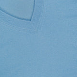 Close-up of a light blue Cashmere V-neck Sweater featuring visible ribbed edging and a WHITE + WARREN label sewn into the neckline.