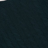 Close-up of the Cashmere Varsity Cable Crewneck Sweater by WHITE + WARREN, featuring a dark green cable-knit design with a white crew neckline trim. A visible clothing tag in the corner displays the WHITE + WARREN brand name.