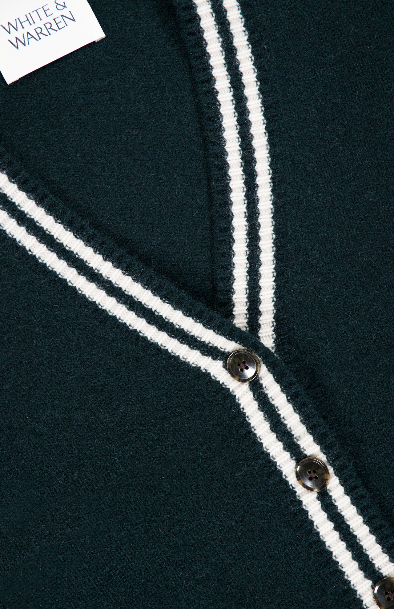 Close-up of a dark green White + Warren Cashmere Varsity Cardigan with white double-stripe trim along the V-neck and front placket.