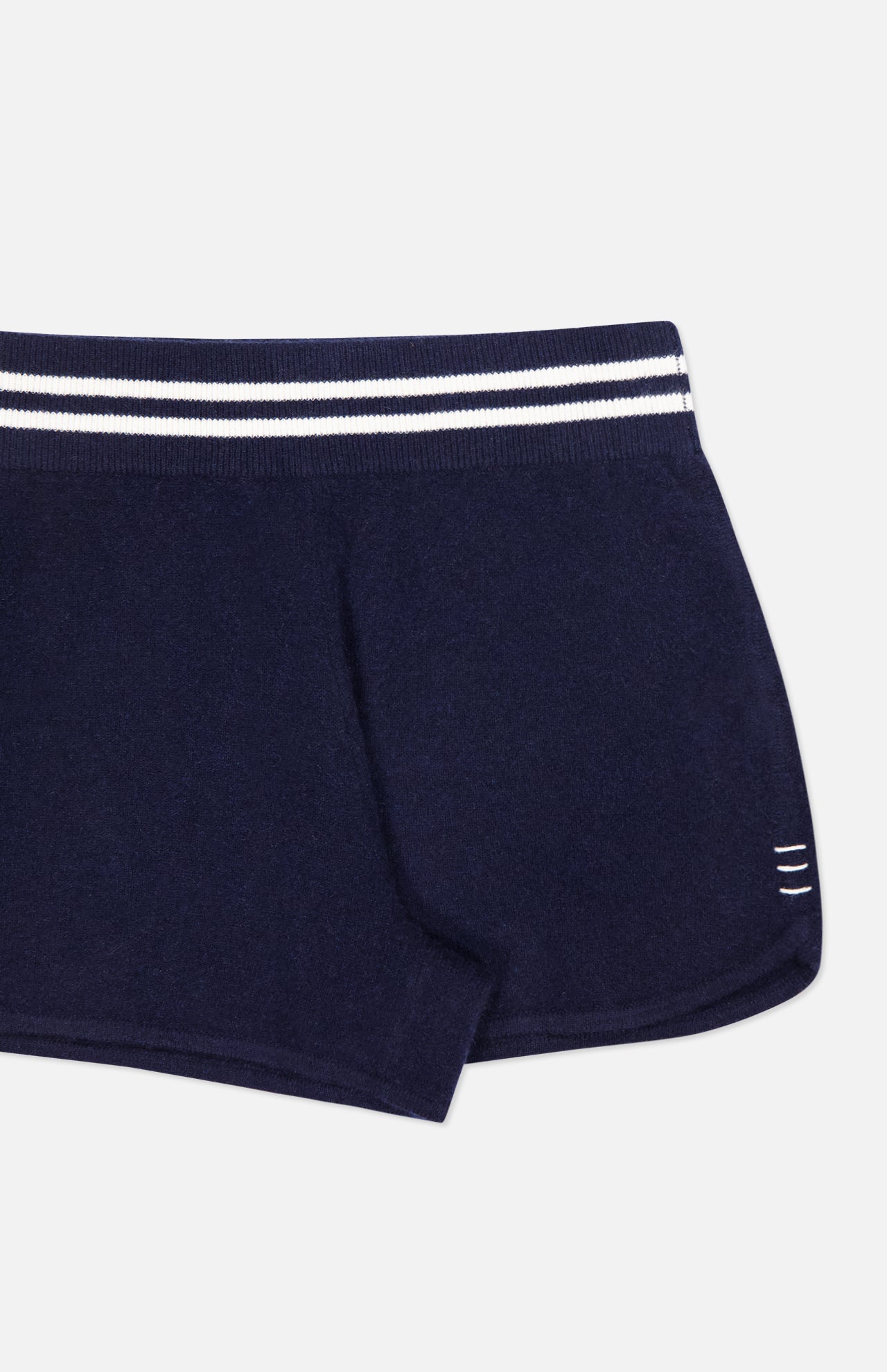 The WHITE + WARREN Cashmere Varsity Shorts feature a navy hue, white double stripe on the elastic waistband, and three small white lines near the hem. Only the right half is shown against a white background.