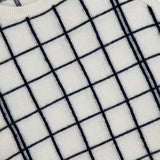 Close-up of the WHITE + WARREN Cashmere Windowpane Vest in cream, showcasing its navy blue windowpane pattern and ribbed trim at the neck and armholes.
