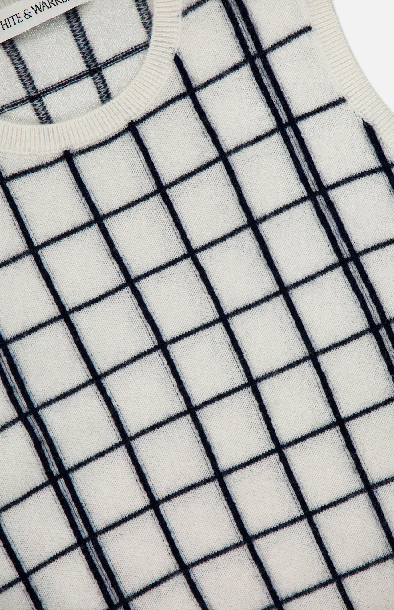 Close-up of the WHITE + WARREN Cashmere Windowpane Vest in cream, showcasing its navy blue windowpane pattern and ribbed trim at the neck and armholes.