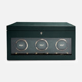 The WOLF British Racing Triple Watch Winder features a green rectangular design with a glass front that showcases three circular compartments, each marked with the WOLF logo. Crafted from premium vegan leather for an elegant and sustainable exterior, this watch winder is designed to wind automatic watches while offering sophisticated storage.