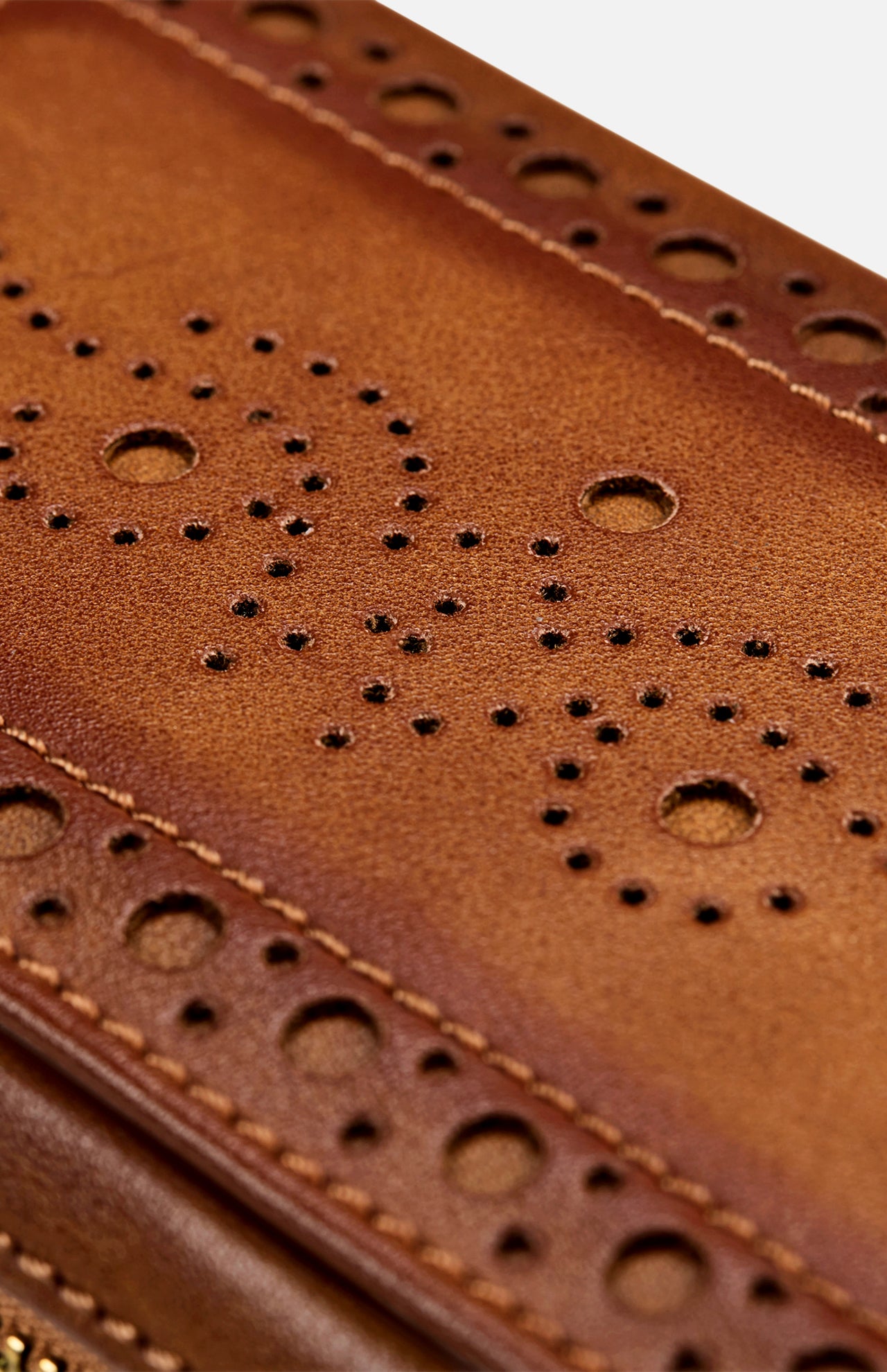Close-up of brown leather with decorative perforated patterns and stitching on the WOLF Brogue 2 Piece Watch Zip Case, highlighting its refined craftsmanship and design.