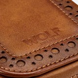 Close-up of the WOLF Brogue 2 Piece Watch Zip Case in brown leather, featuring decorative perforations, detailed stitching, and a gold zipper. The word "WOLF" is embossed on the leather surface, highlighting luxury storage for watches in this elegant case.