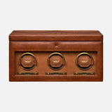 Introducing the Brogue Triple Winder with Storage by WOLF: a rectangular brown leather box adorned with detailed stitching, this luxury watch winder showcases three circular, gold-rimmed compartments labeled WOLF on the front—each equipped with control buttons below—making it an elegant solution for storing and displaying your finest timepieces.