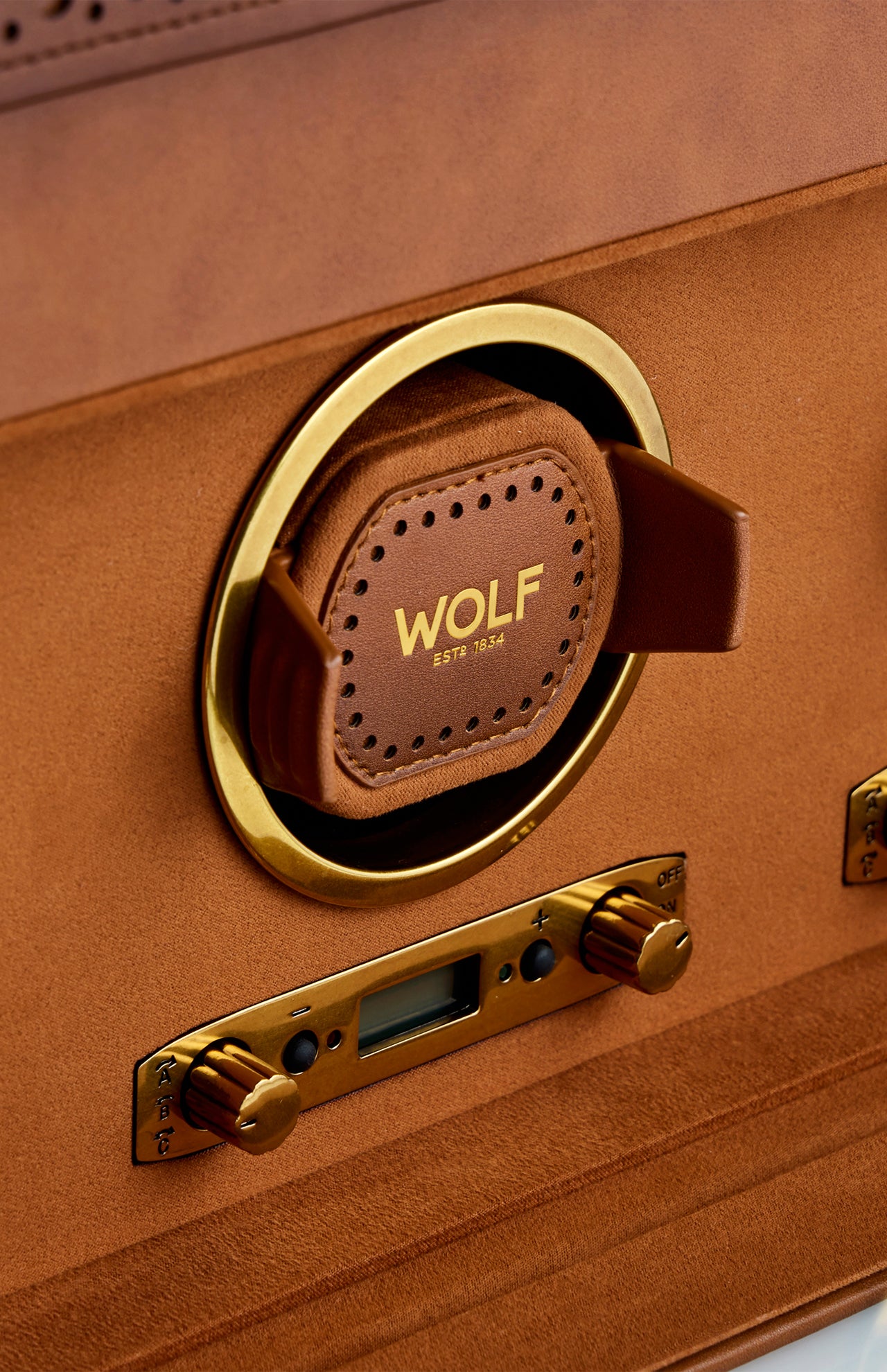 Close-up of the WOLF Brogue Triple Winder with Storage—a brown and gold luxury watch winder featuring a leather cushion and digital display, elegantly set inside a tan suede-lined case for refined watch storage.