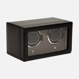 The WOLF Cub Double Winder with Cover is a black rectangular box crafted from premium vegan leather, featuring a glass front that displays two slots for watches inside. Showcasing a sleek, modern design, this luxury accessory blends sophisticated aesthetics with practical functionality and is positioned at an angle against a white background.