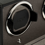 Close-up of the WOLF Cub Double Winder with Cover in black and silver, featuring a vegan leather holder, chrome ring, and a button below—set against a textured dark background. This elegant design exemplifies luxury for your timepiece collection.