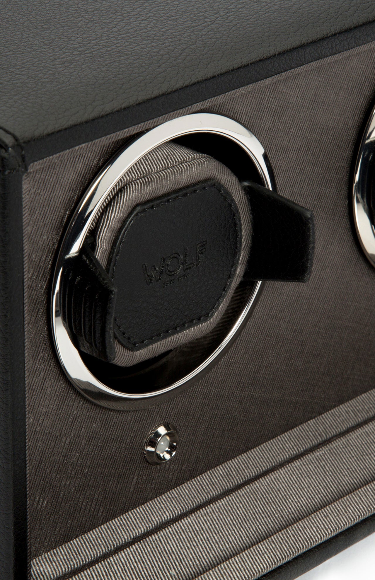 Close-up of the WOLF Cub Double Winder with Cover in black and silver, featuring a vegan leather holder, chrome ring, and a button below—set against a textured dark background. This elegant design exemplifies luxury for your timepiece collection.